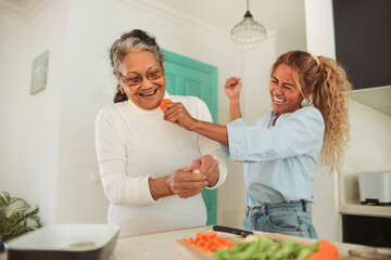 Filipino family cooking together at home - Granddaughter singing and dancing while helping her grandma to cook a traditional asian recipe