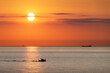 Sunset in the ocean with large sun dusk in orange sky and ships and boats silhouettes. Sea sunrise background. Landscape photography