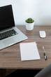 © shutnica - Office at home. Laptop, notebook, pen are on the table near the white wall.