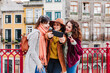 © Eva - three women sightseeing Porto views and taking picture with mobile phone. Travel and friendship concept
