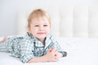 © Юля Шевцова - cute healthy toddler blonde boy in checkered pajama having fun lying in white bed at home