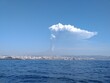 Parossismo del vulcano etna nell'anno 2021 con altissima colonna di cenere e lapilli, vista dal mare con la città di Catania alle pendici