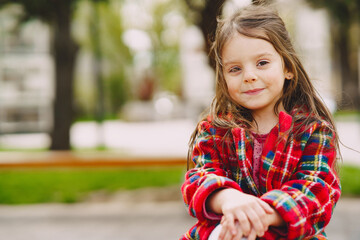 Little girl in a park sitting on a bench