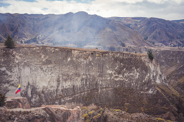 Poster - Beautiful view of rocky mountains with a flag under the cloudy sky in Zumbahuam Ecuador