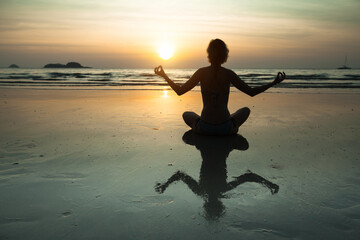 Wall Mural - Yoga woman meditation on amazing sunset sea coast.