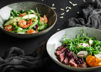 Wall Mural - Fresh salads with avocado, shrimps, beef steak, tomatoes, green leaves, arugula, spinach, chicken breast and sweet sauce on dark wooden background. Healthy food, clean eating, closeup