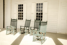 Group Of Empty Antique Wooden Rocking Chairs On Front Porch.