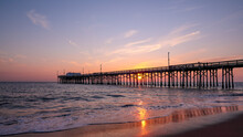 Scenic Sunset Over The Pacific Ocean. A Setting Sun Behind The Long Pier, Irvine, Orange County, California