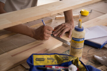 Carpenter measuring wooden board with ruler with scale in workshop. Joinery work on the production of wooden furniture. Small Business Concept