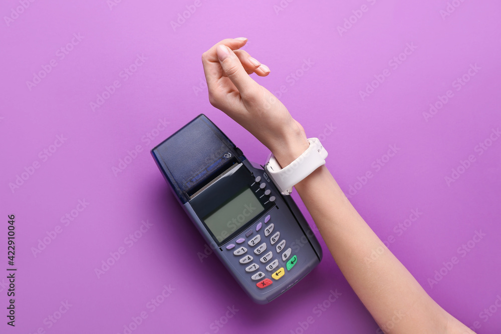 Female hand with smart watch and payment terminal on color background