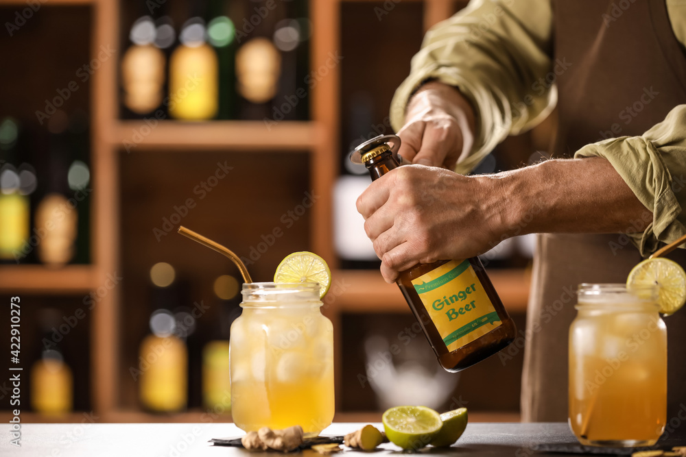 Bartender opening bottle of fresh ginger beer on table in bar - obrazy, fototapety, plakaty 
