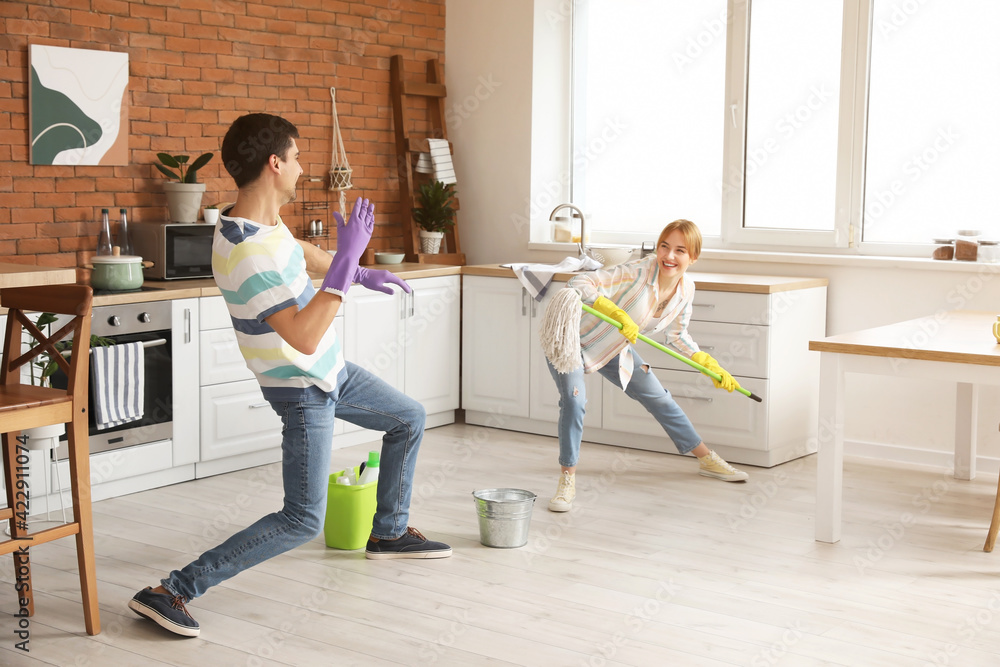 Young couple having fun while cleaning their kitchen