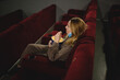 © Aleksandra Iarosh - young woman in medical mask eating popcorn sitting in the cinema