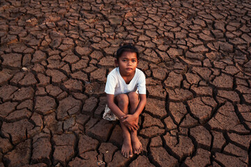 a poor asian child a drought, sorrow, sits on a dry ground, hopes and drought.
