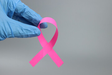 Pink ribbon in the hand of a doctor or nurse, breast cancer struggle symbol