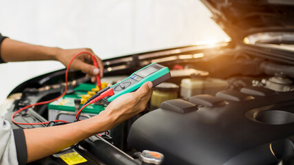 A technician is checking the car battery for availability.;