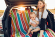 © Shopping King Louie - Travel - family ready to go on summer vacation, Happy mom with a small child in the trunk of a car
