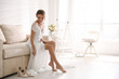Gorgeous bride in beautiful wedding dress sitting on sofa in room. Space for text