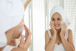 © New Africa - Happy mature woman applying cleansing foam onto face near mirror in bathroom