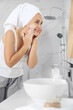 © New Africa - Happy mature woman washing face in bathroom