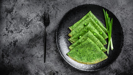 Canvas Print - Green vegan crepes with spinach on dark background. Healthy breakfast, vegetarian food, banner, menu recipe place for text, top view