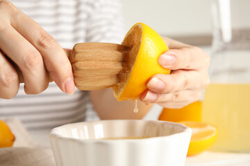 Woman squeezing lemon juice with wooden reamer, closeup