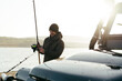 © fotofabrika - Young fisherman standing near his car and holding fishing equipment