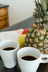 two cups of coffee and pineapple