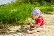 baby 1 year old plays on a sandy beach by the river on a sunny day, selective focus