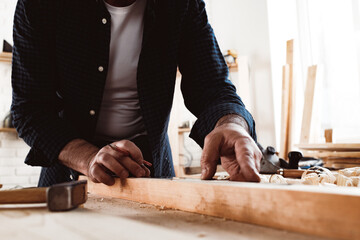 Carpenter makes pencil marks on a wood plank