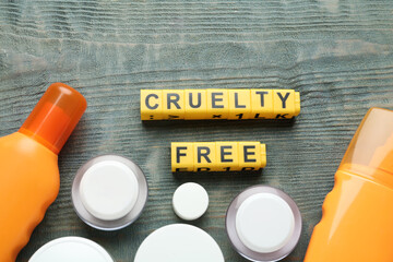 Flat lay composition with words Cruelty Free and different cosmetic products not tested on animals against light blue wooden background