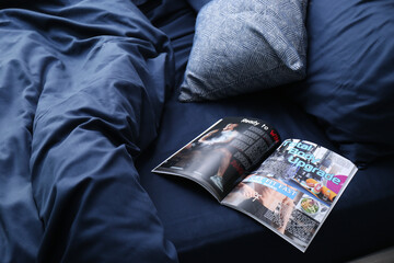 Open magazine on bed with stylish silky linens