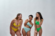 Beautiful young women with different body shapes wearing colorful underwear looking happy, laughing while posing together in the studio over white background