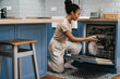 © Drobot Dean - Happy black woman smiling while using dishwasher at home kitchen