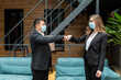 © Liubomir - Male and female businesspeople concluding a business meeting are greeted by touching their elbows to each other, wearing protective medical masks