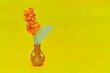 Żółty ręcznie robiony kwiat z papieru w brązowym wazoniku na żółtym tle