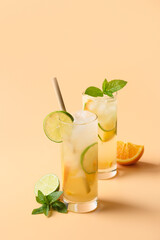 Wall Mural - Cold and refreshing lemonade or cocktail with orange and lime slice on beige vertical background. Summer drink.