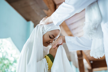 portrait of girls kissing the hand of a male Muslim teacher before returning to home from the mosque