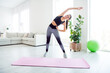 © deagreez - Full length photo of charming positive lady standing near fitness carpet hand on waist stretch morning workout indoors