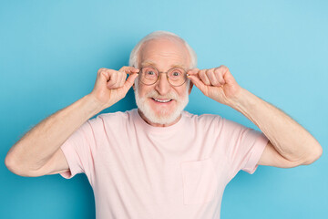 Poster - Photo of aged man pensioner happy positive smile excited hands touch glasses isolated over blue color background