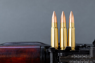 Three bullets on Kalashnikov assault rifle against blurred gray background. Cartridges 7.62 caliber for ak 47, closeup, selective focus with copy space