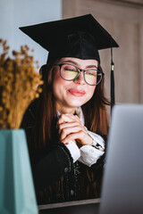 Happy young caucasian woman celebrating college graduation during a video call with friend or family.