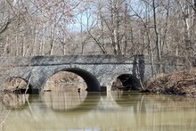 The Old Stone Bridge Over The Creek In The Park.