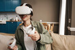 © Drobot Dean - Excite white woman playing online game with vr glasses and controllers
