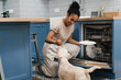 © Drobot Dean - Smiling black woman feeding her dog while using dishwasher