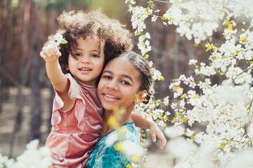 Sweet family portrait of two lovely sisters in springtime bloom