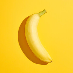 Wall Mural - Banana with hard shadow on yellow background, from above