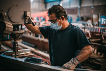 a man works with an industrial machine drilling a piece of metal