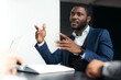 © DmitryStock - Stylish serious african american man in the office communicates with workers gesturing with his hands
