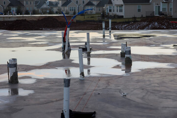 Pouring the foundation for plumbing pipes coming out of concrete slab a new house with suburbs